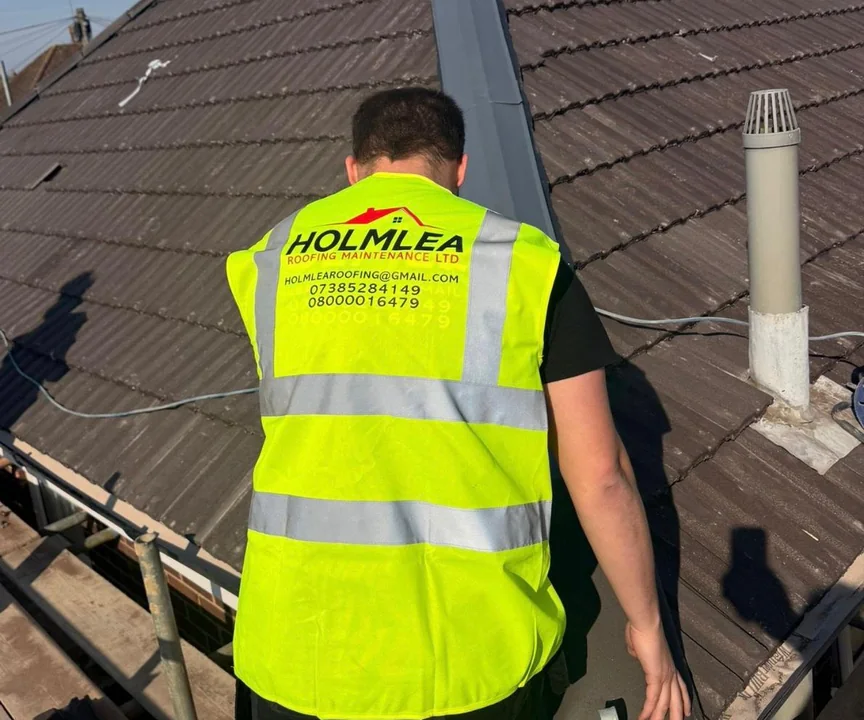 A Holmlea roofer at work on the eaves of a concrete tile roof, beside the soil vent pipe