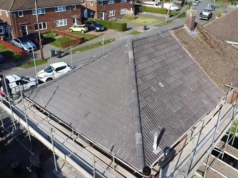 New grey concrete tile roof on a semi-detached house, scaffold still up, seen from the drone